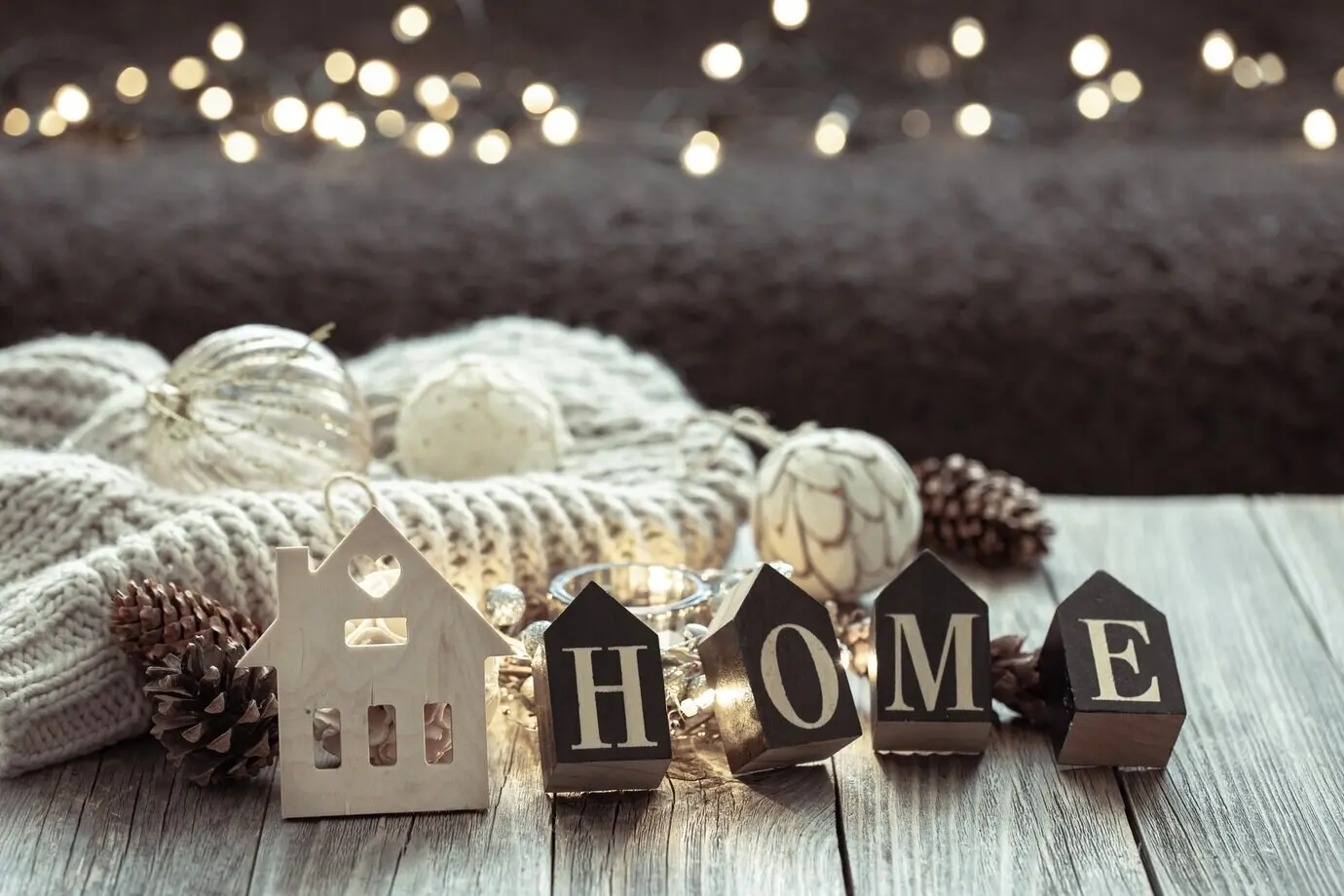 Nahaufnahme von Holzbuchstaben, die das Wort „home“ bilden, vor unscharfem Hintergrund mit Bokeh.