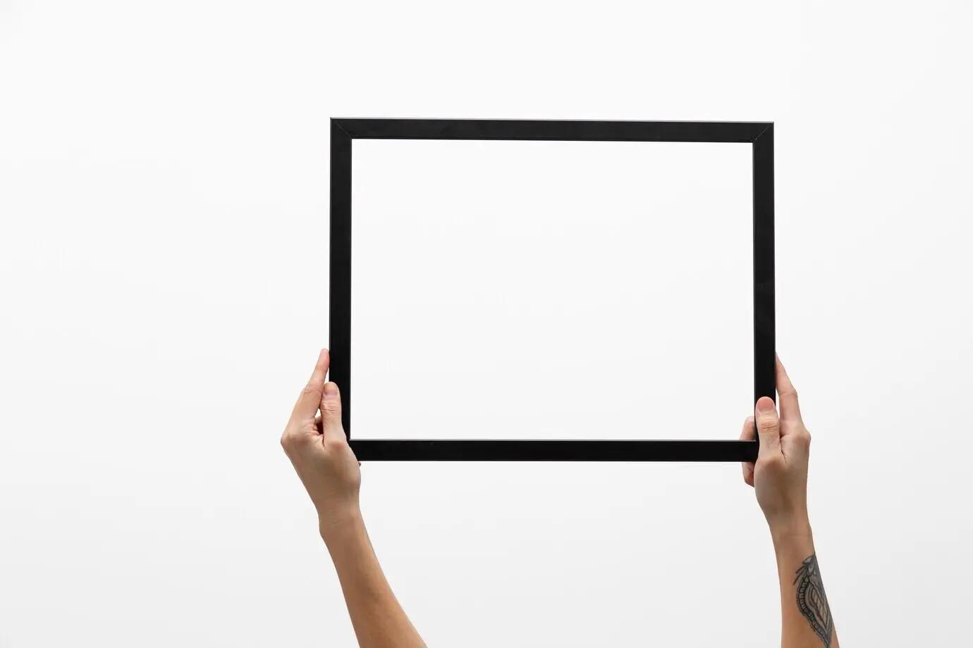 Hände mit Tätowierung halten einen dunklen Rahmen.